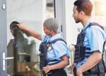 Crime, patrol and police knocking on a door for justice, security and law at a home. Together, teamwork and a black woman and man at a house for service, check and helping the community for work