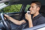 Man in car blowing into breathalyzer