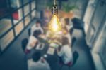 Business team is discussing together with a glowing light bulb hanging above them as a bright idea.