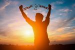 Silhouette image of a man with broken chains on his wrist during sunset